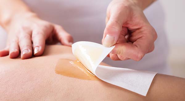 peeling back waxing strip during a back waxing session