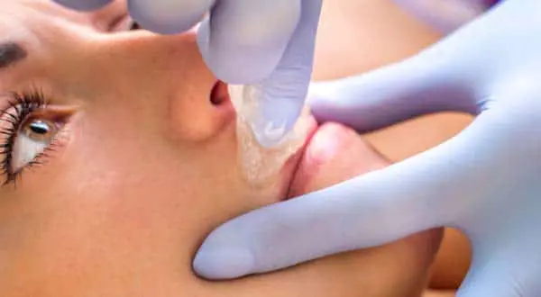 a woman lip is getting cleaned before lip waxing